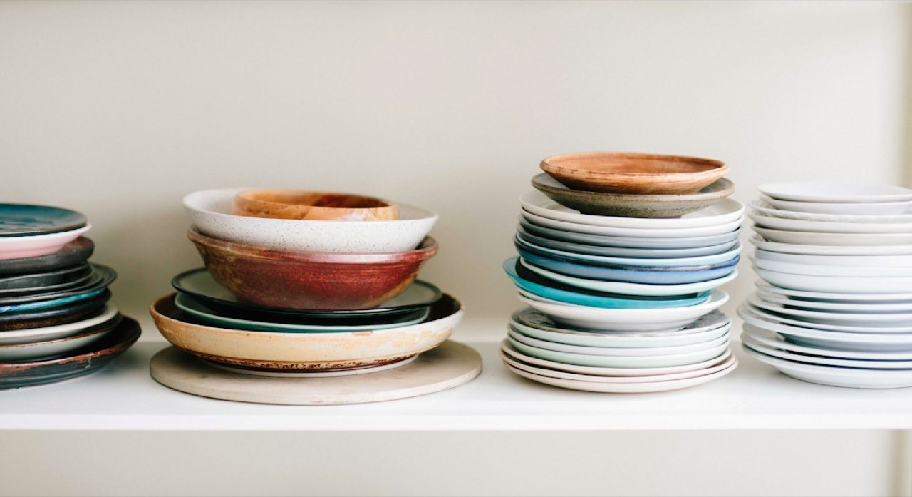 Stacks of speckled ceramic plates and bowls on a shelf